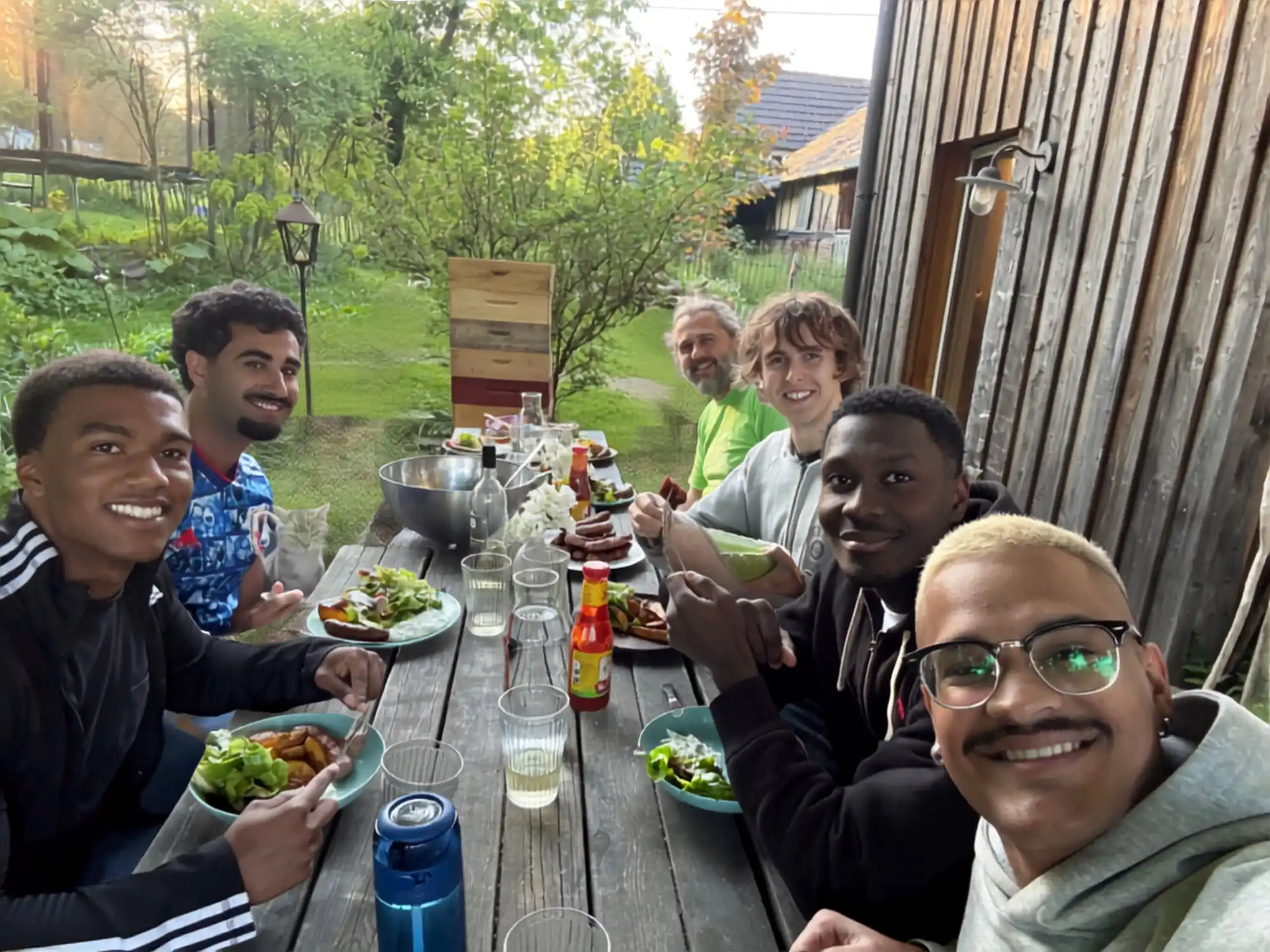 Große Tafel im Freien: WWOOFer:innen und Gastgeber beim gemeinsamen Abendessen vor dem Hof.
