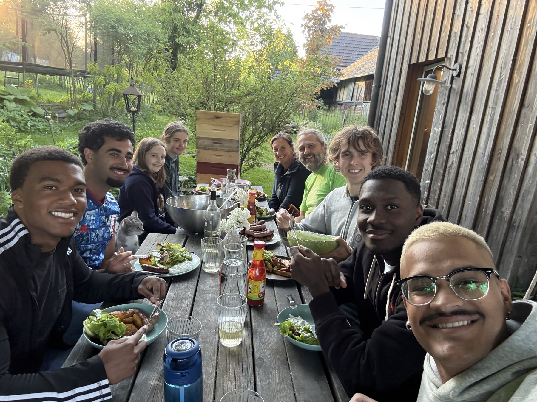 Große Tafel im Freien: WWOOFer:innen und Gastgeber beim gemeinsamen Abendessen vor dem Hof.